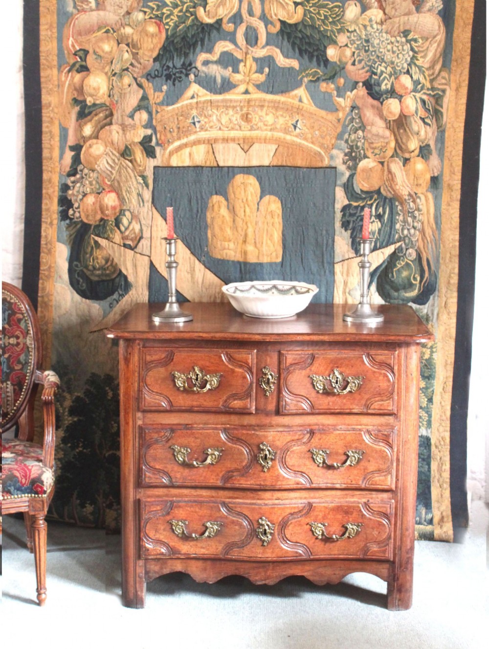 An 18th-century French Provincial walnut commode featuring three carved drawers with serpentine fronts and brass hardware.