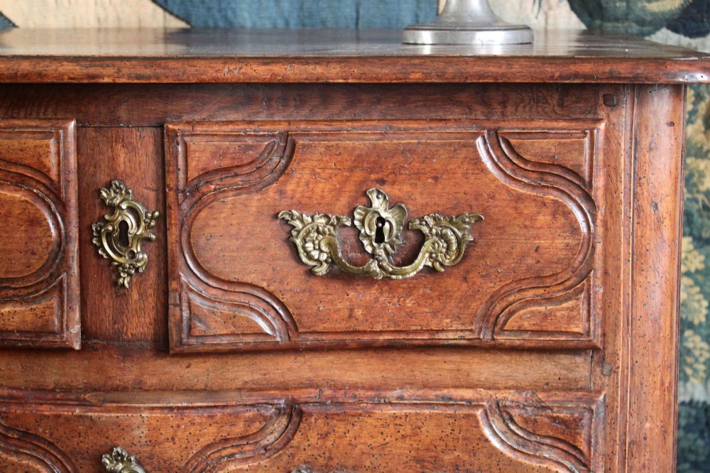 An 18th-century French Provincial walnut commode featuring three carved drawers with serpentine fronts and brass hardware. View III