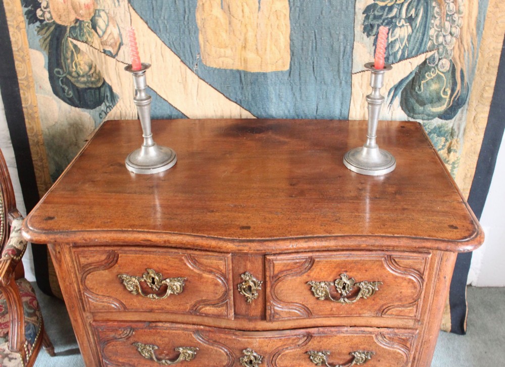 An 18th-century French Provincial walnut commode featuring three carved drawers with serpentine fronts and brass hardware. View IV