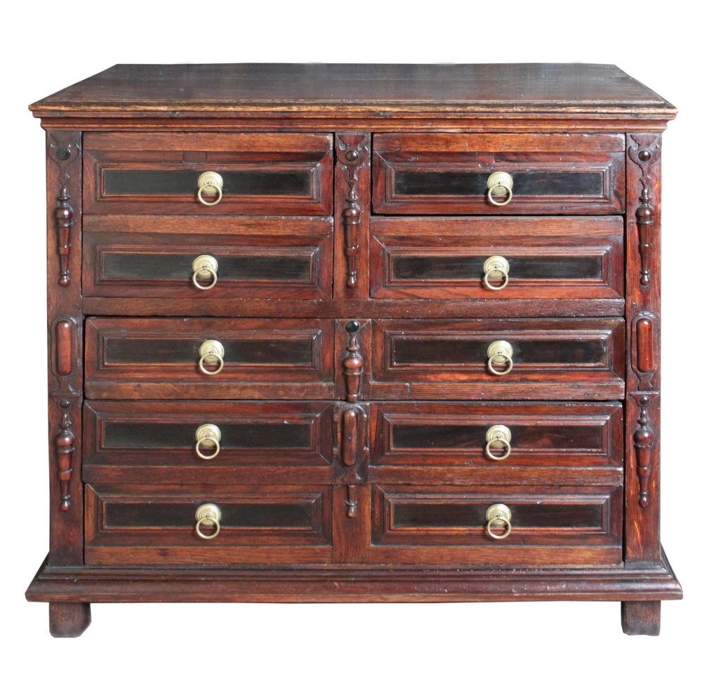 Dark brown Charles II oak chest of drawers featuring geometric moulded drawer fronts and brass drop handles. View III