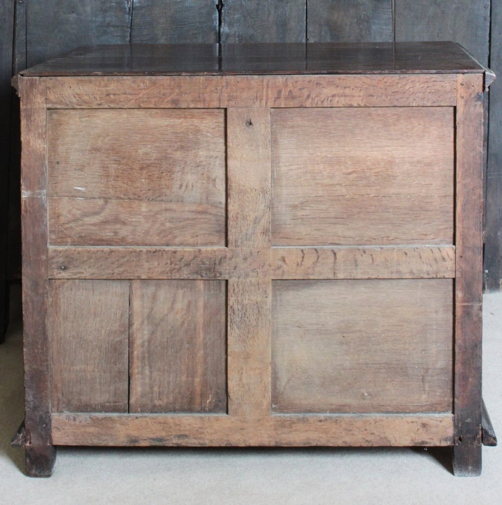 Dark brown Charles II oak chest of drawers featuring geometric moulded drawer fronts and brass drop handles. View IV