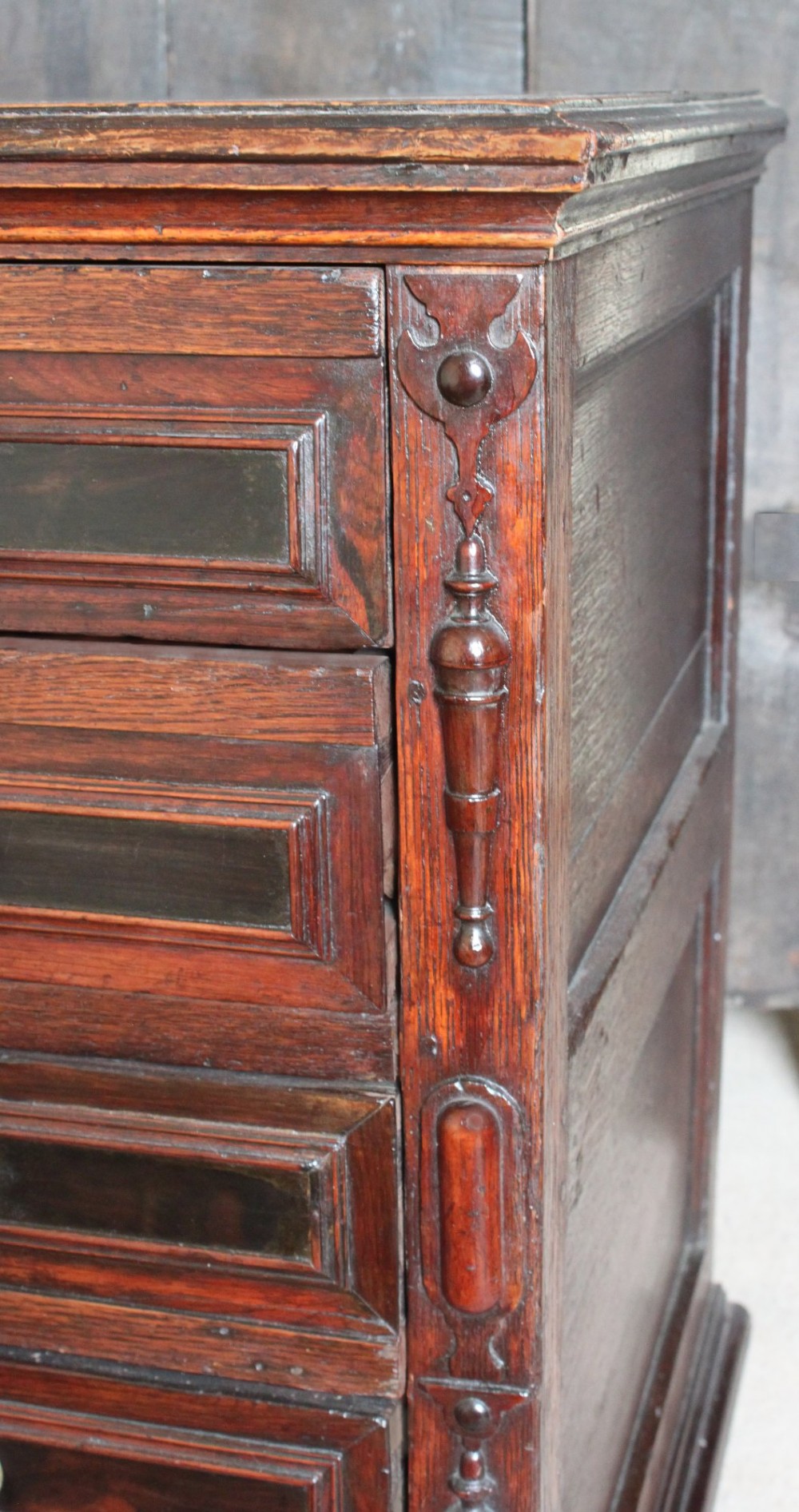 Dark brown Charles II oak chest of drawers featuring geometric moulded drawer fronts and brass drop handles. View VI