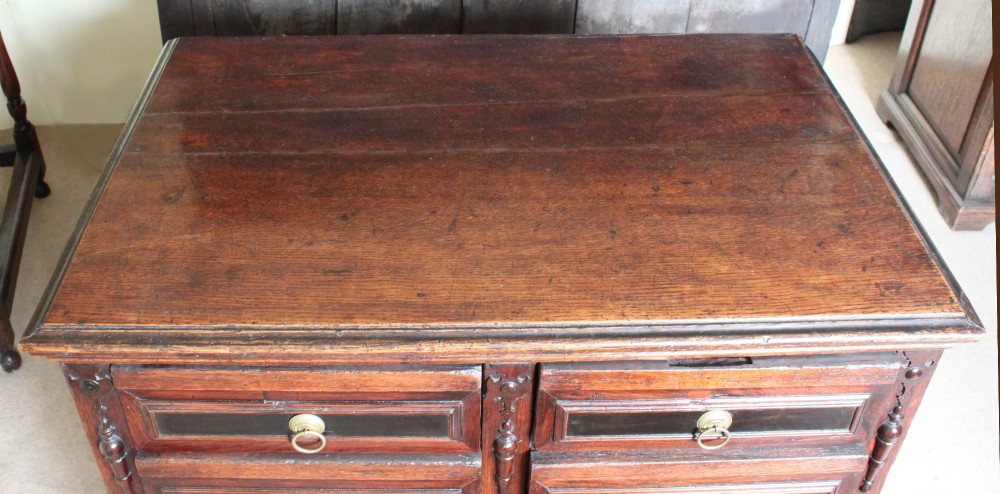 Dark brown Charles II oak chest of drawers featuring geometric moulded drawer fronts and brass drop handles. View VII