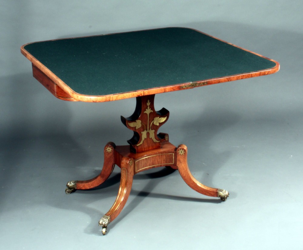 A pair of Regency rosewood card tables featuring brass foliate inlay, fold-over tops, pedestal bases, and splayed legs with brass paw castors. View IV
