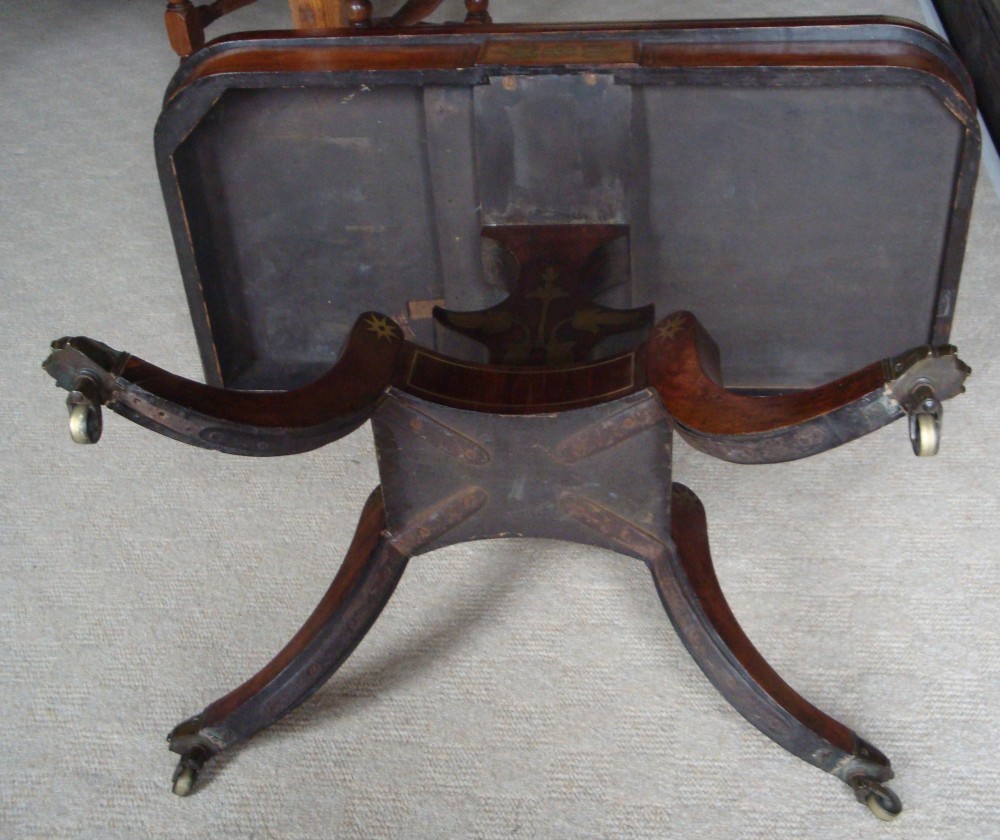 A pair of Regency rosewood card tables featuring brass foliate inlay, fold-over tops, pedestal bases, and splayed legs with brass paw castors. View V