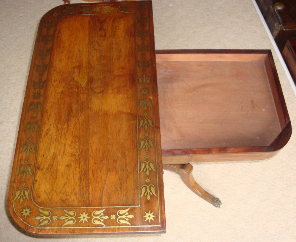 A pair of Regency rosewood card tables featuring brass foliate inlay, fold-over tops, pedestal bases, and splayed legs with brass paw castors. View VI