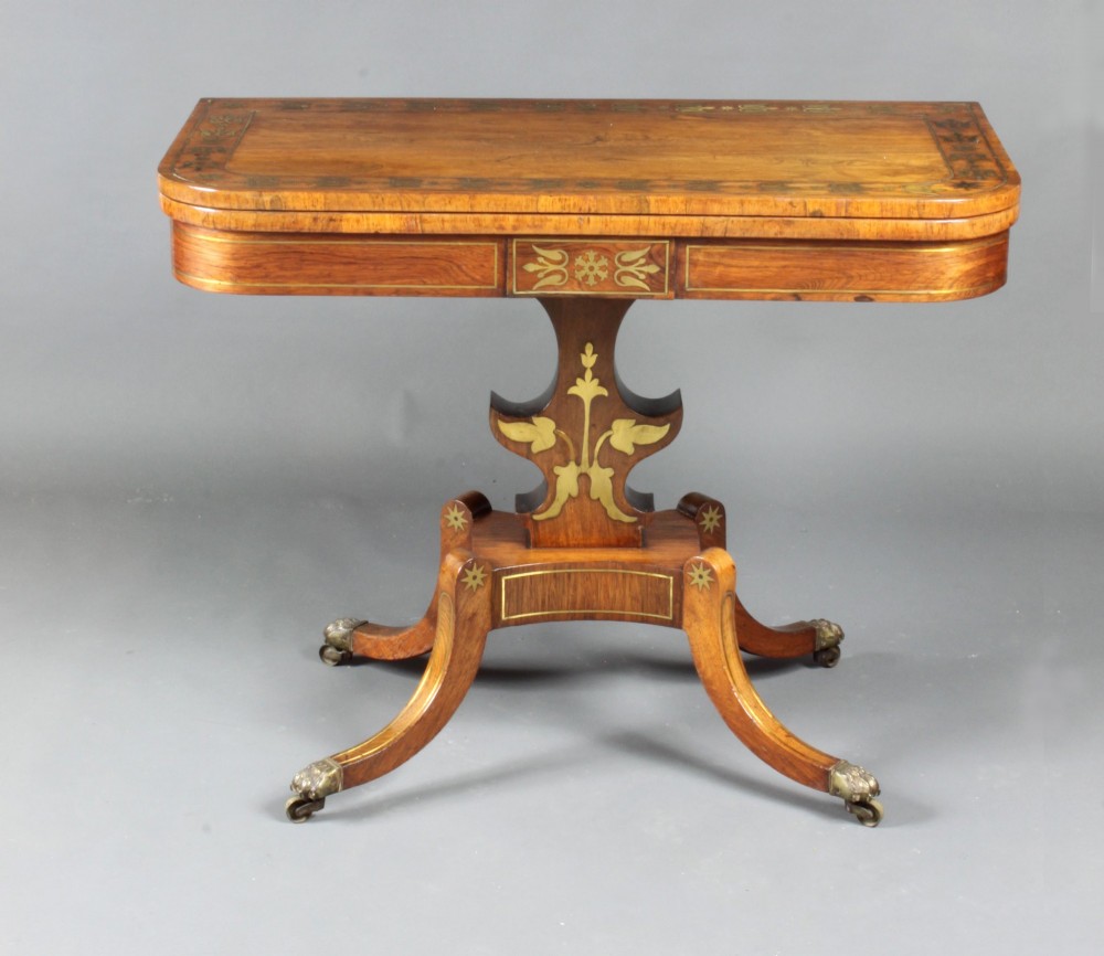 A pair of Regency rosewood card tables featuring brass foliate inlay, fold-over tops, pedestal bases, and splayed legs with brass paw castors. View VII
