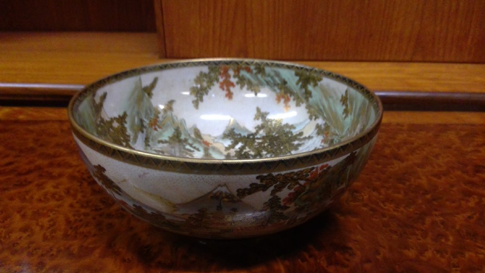 A circular Japanese Satsuma ceramic bowl featuring a hand-painted interior landscape with pagodas, trees, mountains, and gilt accents. View II