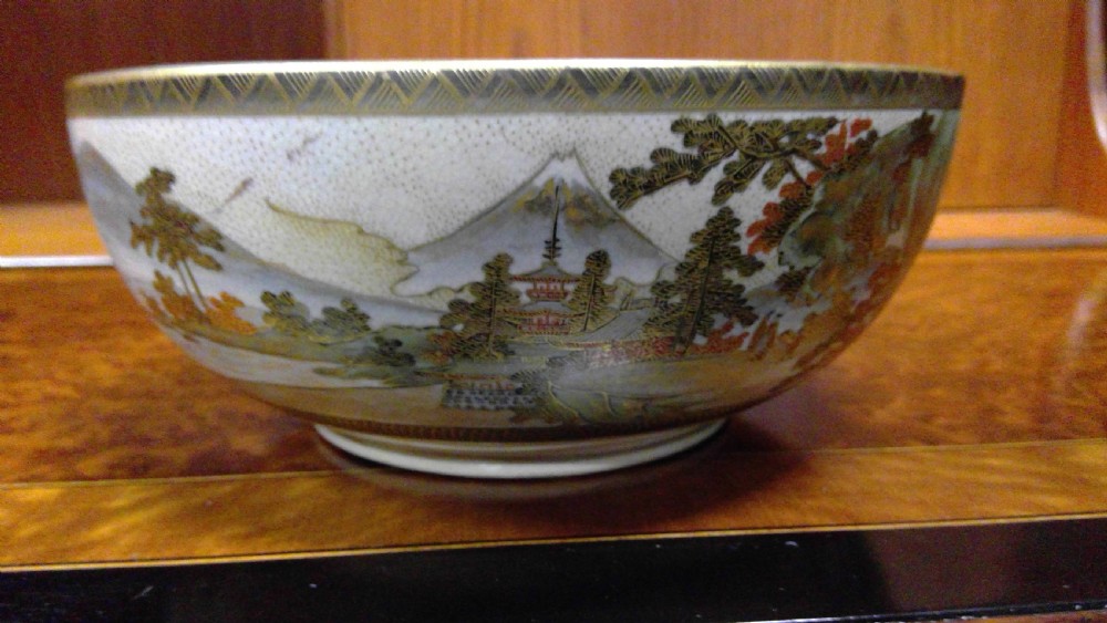 A circular Japanese Satsuma ceramic bowl featuring a hand-painted interior landscape with pagodas, trees, mountains, and gilt accents. View V