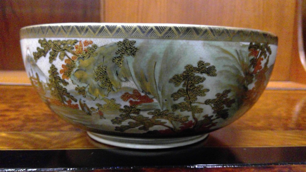 A circular Japanese Satsuma ceramic bowl featuring a hand-painted interior landscape with pagodas, trees, mountains, and gilt accents. View VI