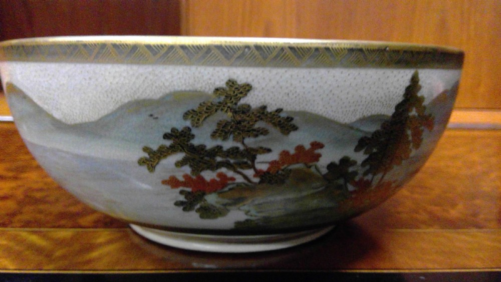 A circular Japanese Satsuma ceramic bowl featuring a hand-painted interior landscape with pagodas, trees, mountains, and gilt accents. View IX
