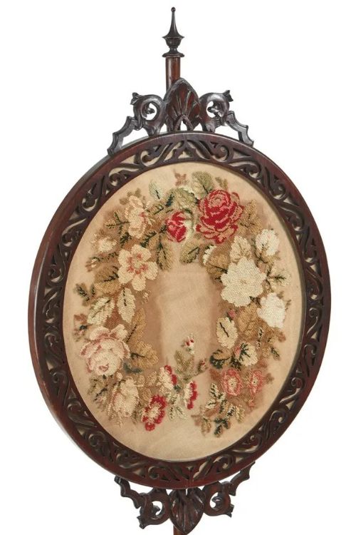 fig 2. A Victorian carved mahogany tripod pole screen featuring an oval frame with a floral needlepoint tapestry, set atop a turned pole with carved scroll feet and a top finial.
