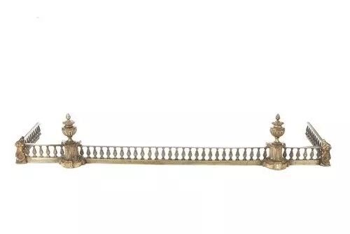 fig 1. An antique Victorian brass fireplace fender featuring a central balustrade rail flanked by corner pedestals topped with urn finials.