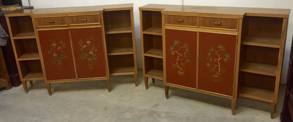 A matching pair of low mid-century breakfront bookcases in light wood with hand-painted red central doors and open side shelving.