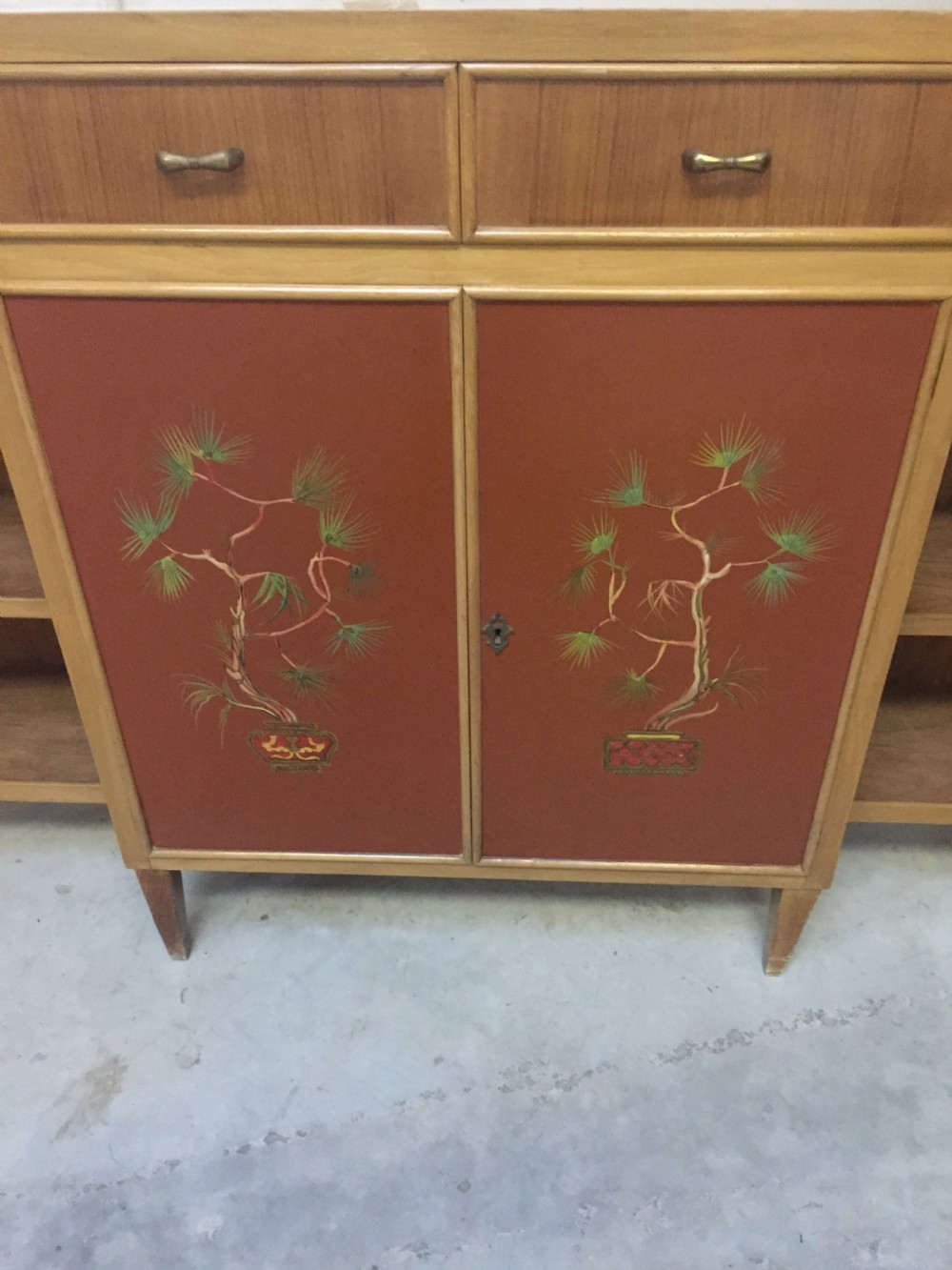 A matching pair of low mid-century breakfront bookcases in light wood with hand-painted red central doors and open side shelving. View II