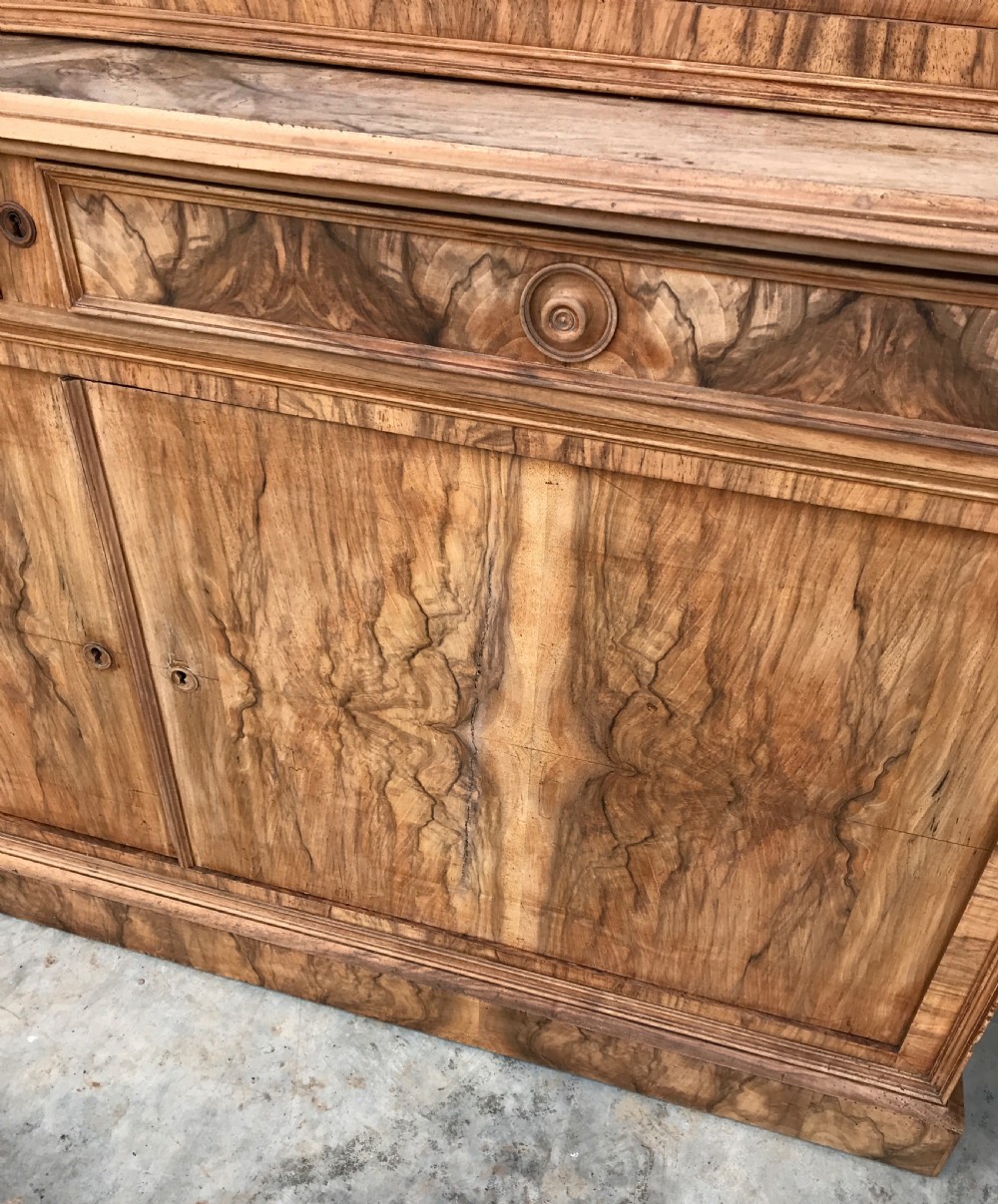 A tall 19th-century figured walnut glazed bookcase featuring double glass doors above two frieze drawers and a double-door lower cupboard base. View V