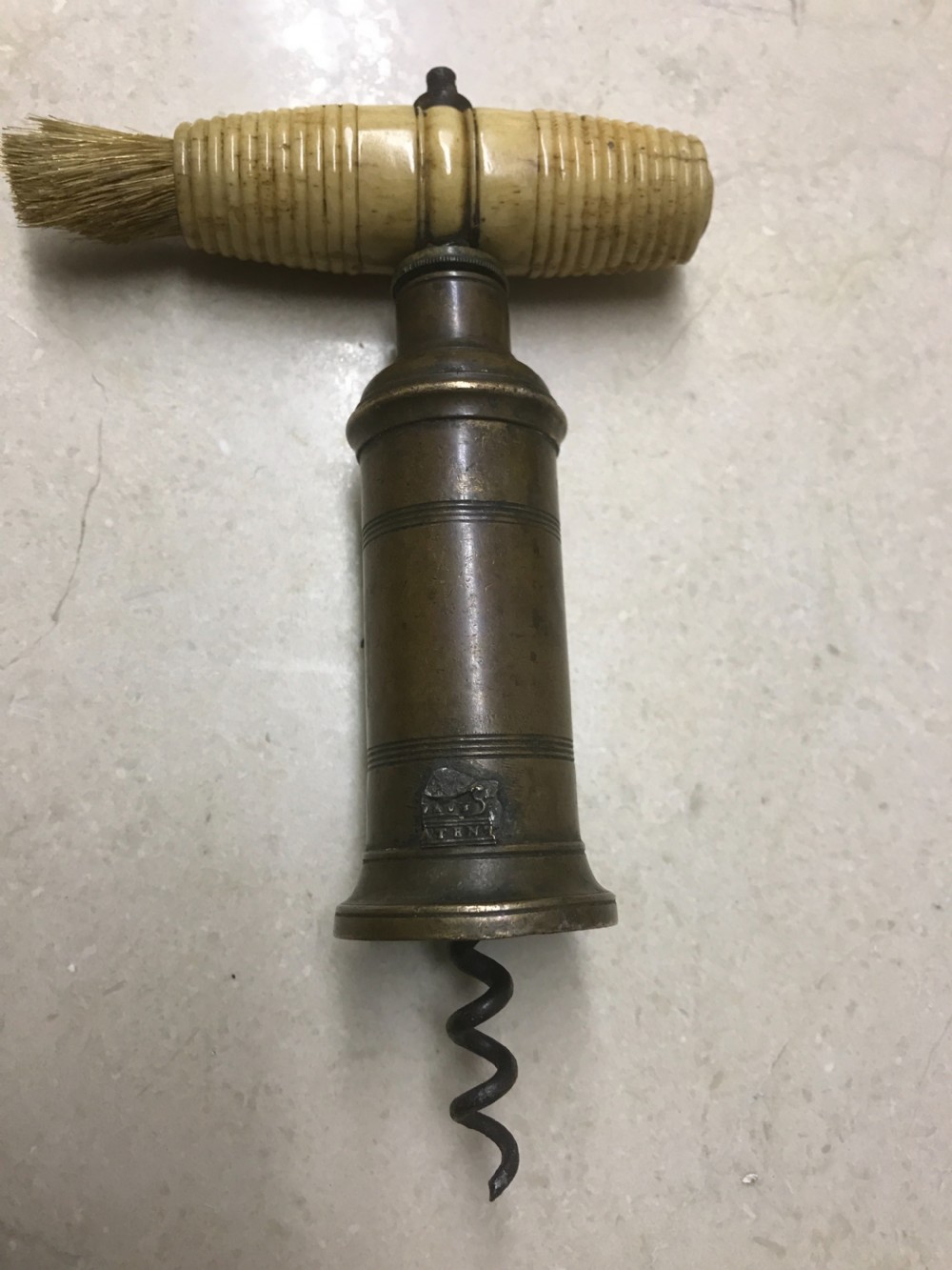 An antique Victorian mechanical brass corkscrew with a ribbed turned bone handle, an integrated dusting brush, and a steel helix worm at the base.