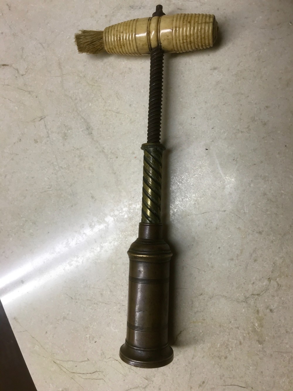 An antique Victorian mechanical brass corkscrew with a ribbed turned bone handle, an integrated dusting brush, and a steel helix worm at the base. View III