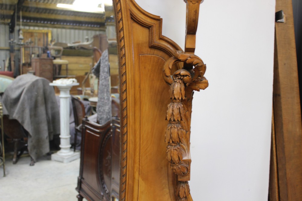 A French carved walnut dressing table featuring a large central oval mirror, twin side sconces with fabric shades, pedestals with glass tops, and a low red velvet footrest. View IV