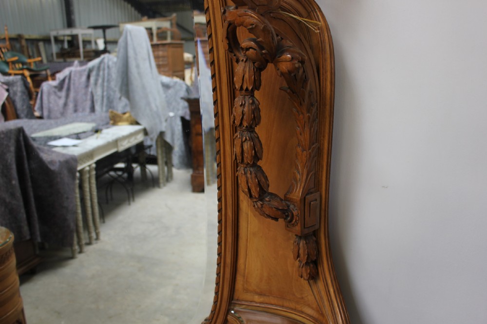 A French carved walnut dressing table featuring a large central oval mirror, twin side sconces with fabric shades, pedestals with glass tops, and a low red velvet footrest. View XII