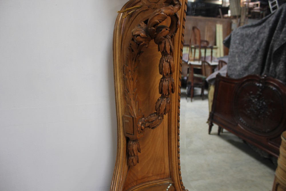 A French carved walnut dressing table featuring a large central oval mirror, twin side sconces with fabric shades, pedestals with glass tops, and a low red velvet footrest. View XIII