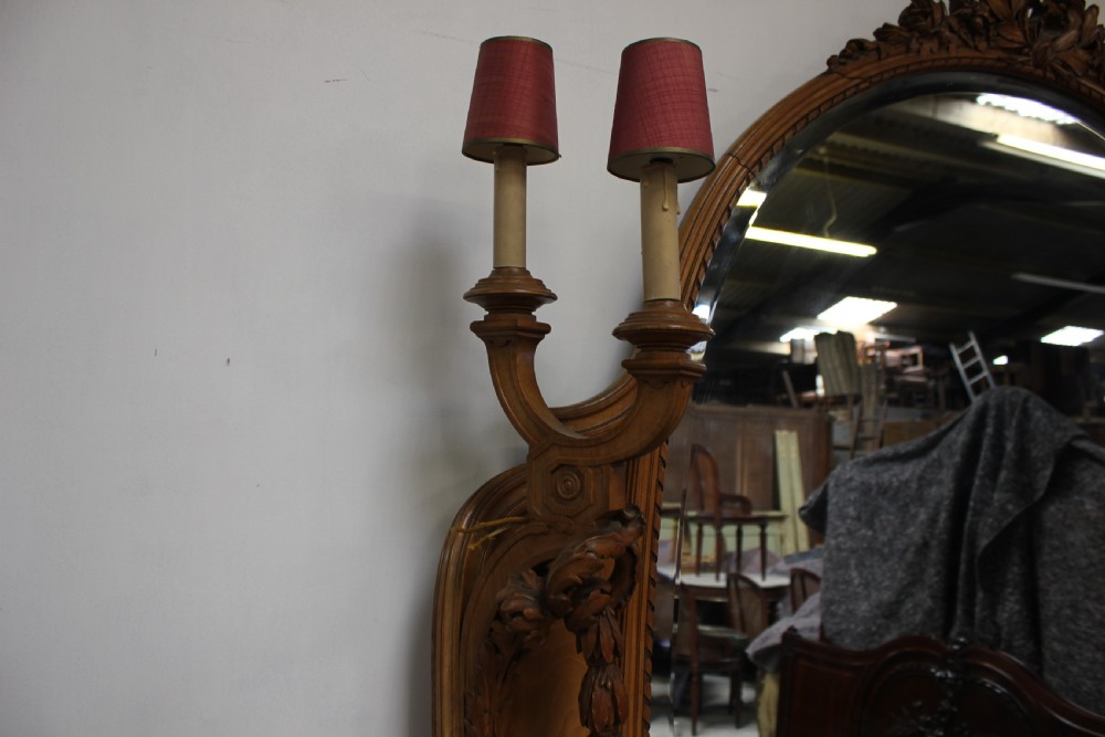 A French carved walnut dressing table featuring a large central oval mirror, twin side sconces with fabric shades, pedestals with glass tops, and a low red velvet footrest. View XIV