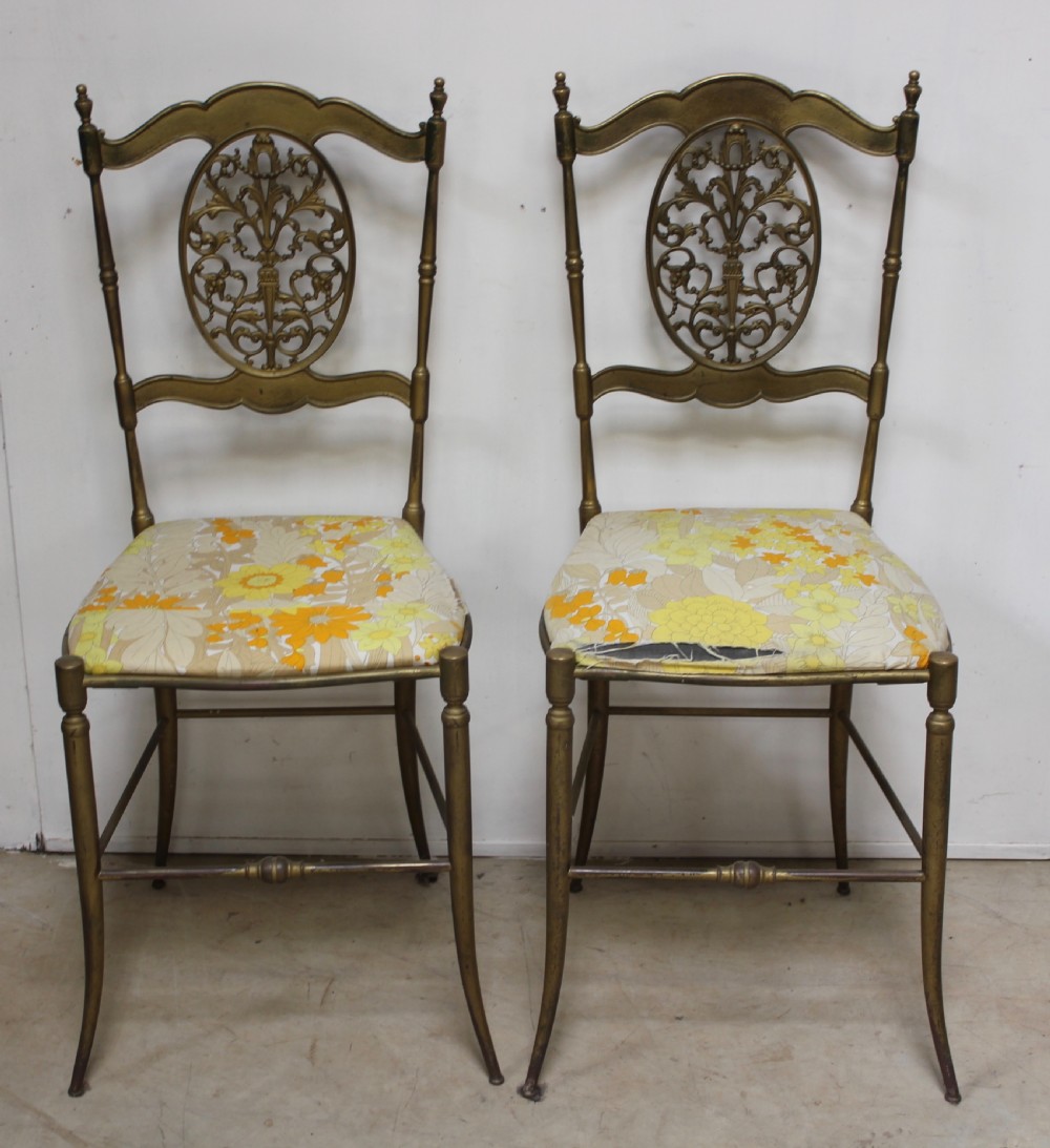 A pair of gold-toned brass side chairs featuring oval openwork splat backs, turned stretchers, and yellow floral fabric seats. View III