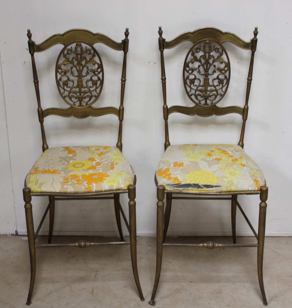 A pair of gold-toned brass side chairs featuring oval openwork splat backs, turned stretchers, and yellow floral fabric seats. View IV