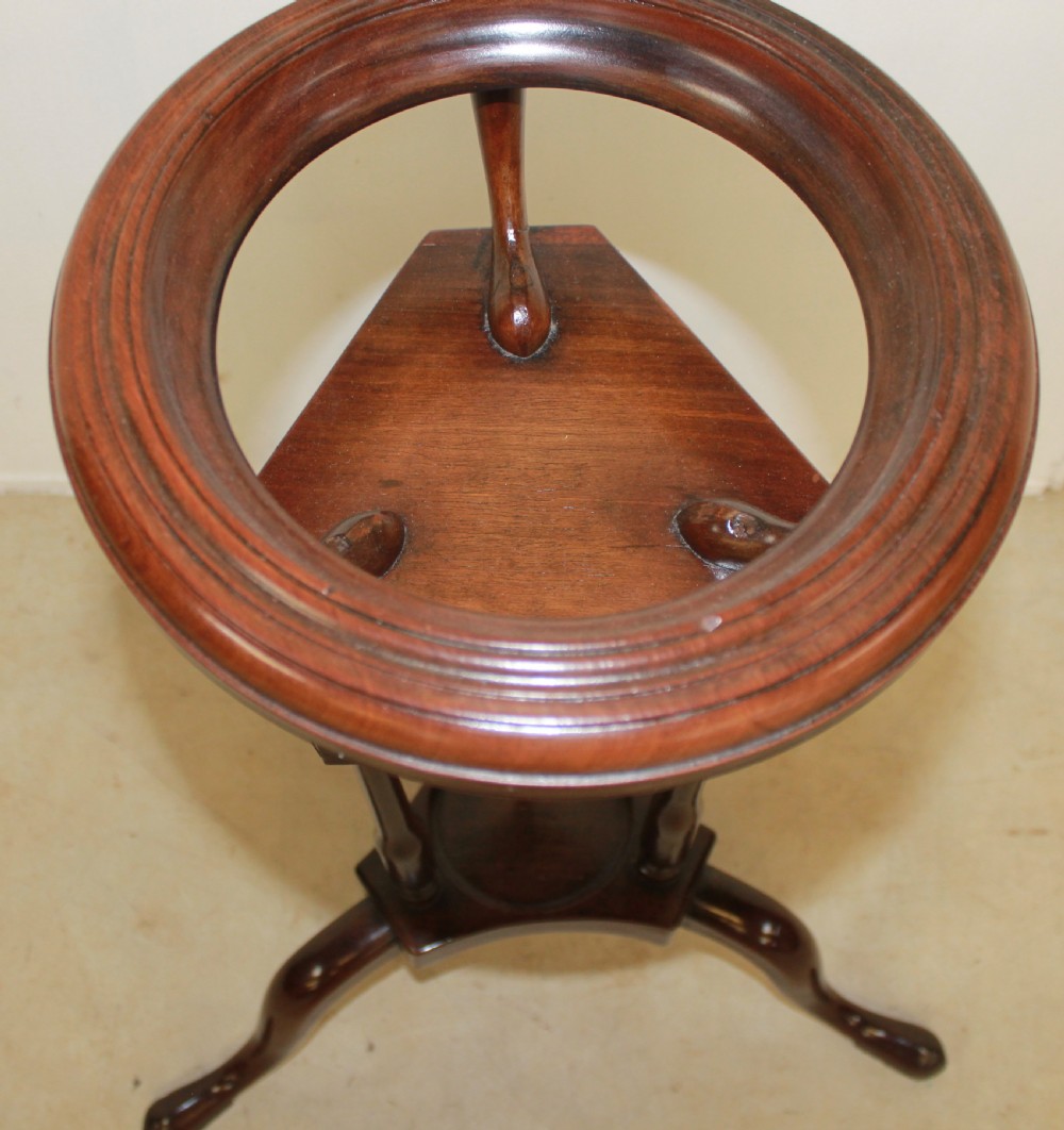 A dark mahogany Georgian tripod washstand featuring a circular top ring, central drawer tier, and curved tripod legs. View II