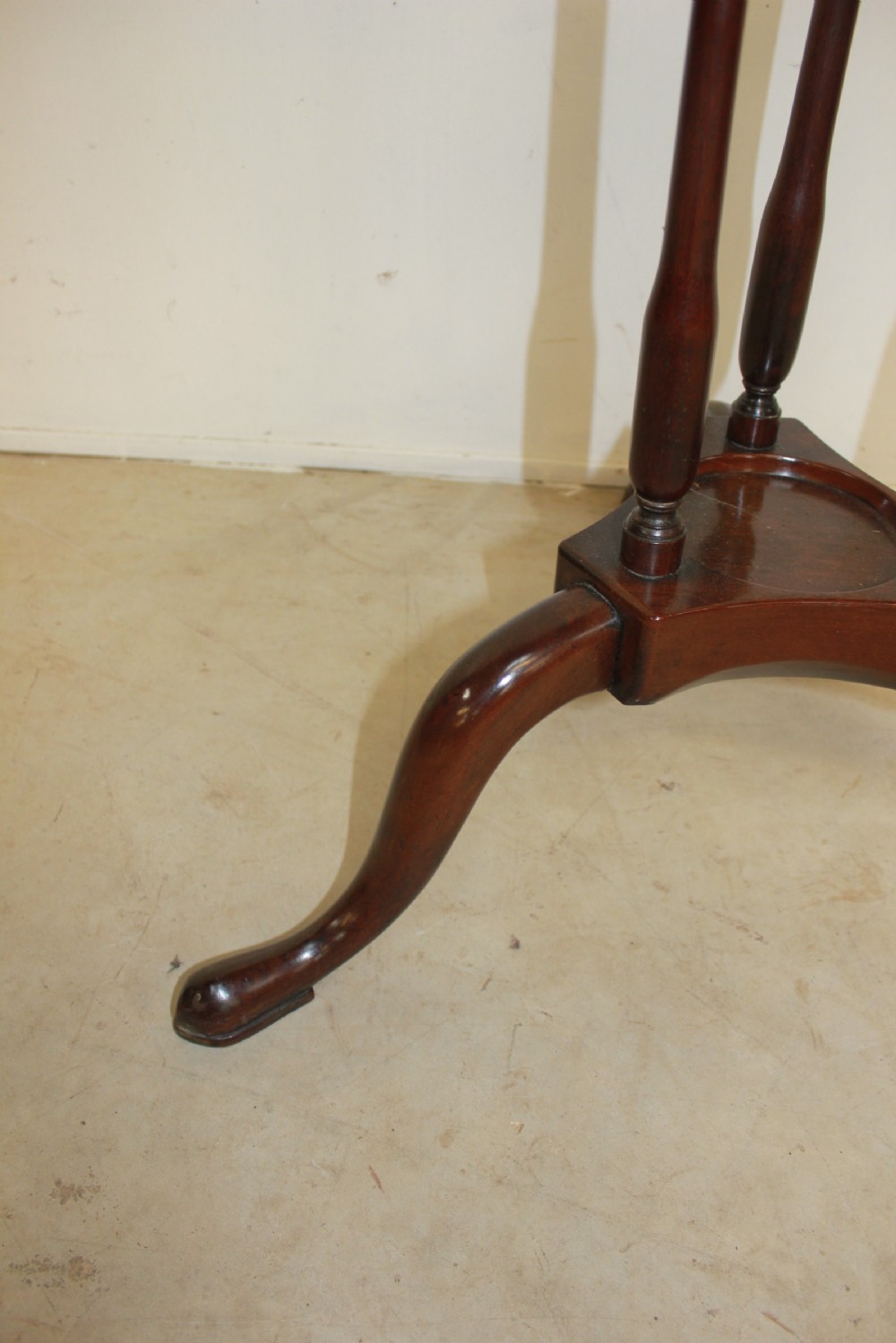 A dark mahogany Georgian tripod washstand featuring a circular top ring, central drawer tier, and curved tripod legs. View III