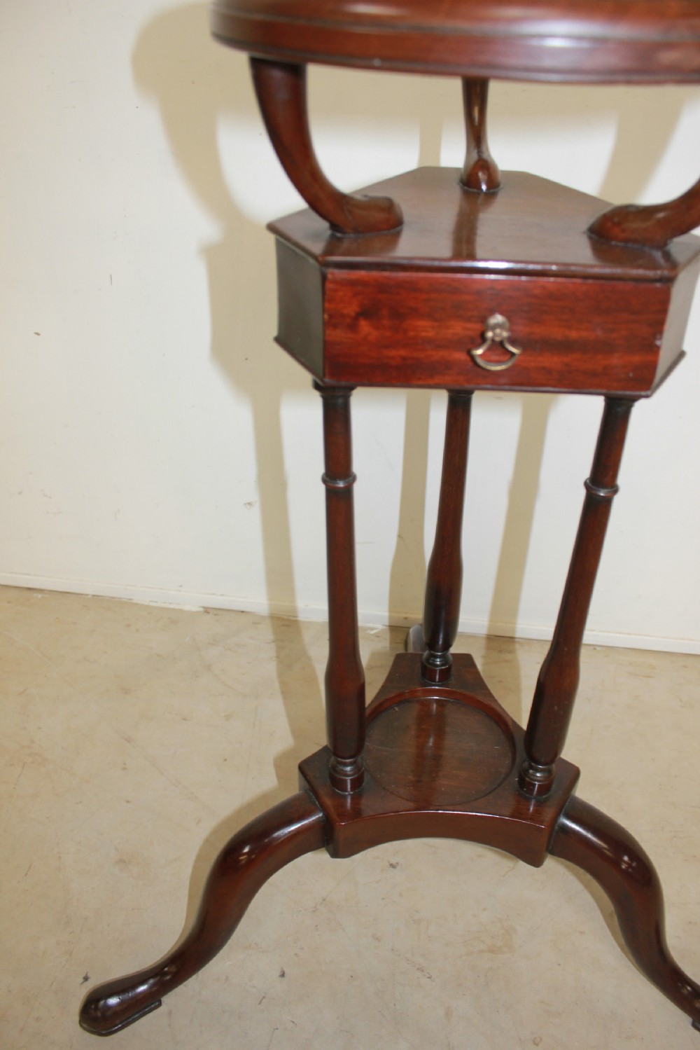 A dark mahogany Georgian tripod washstand featuring a circular top ring, central drawer tier, and curved tripod legs. View IV