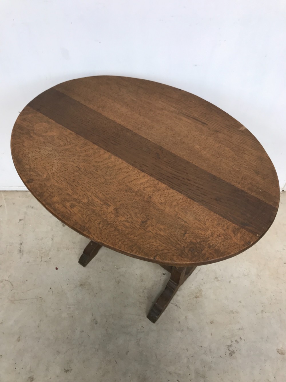 A dark oak miniature wine table featuring an oval top resting on turned vertical posts and a V-shaped support on trestle feet. View II