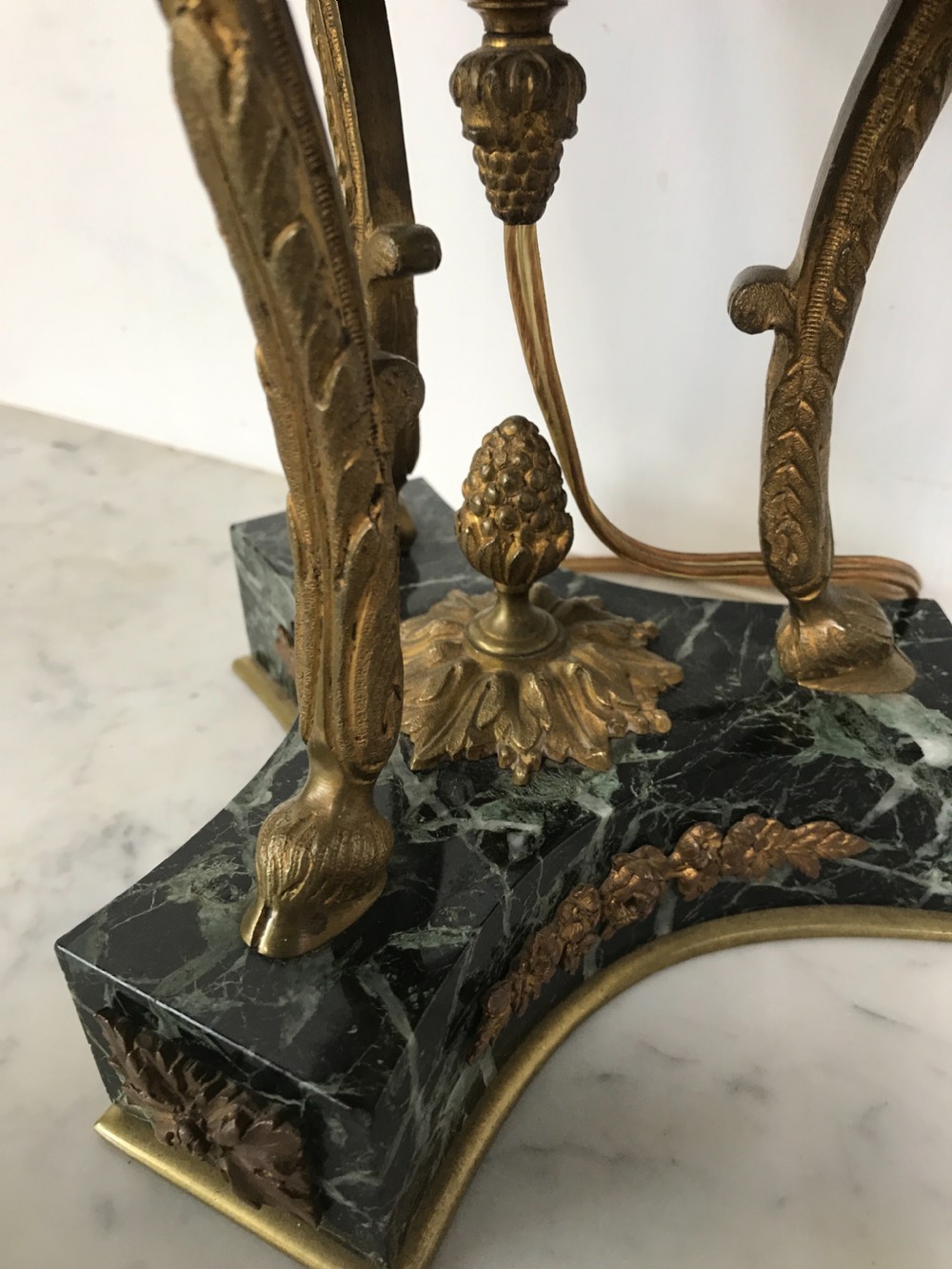 A pair of Neoclassical style table lamps fashioned as dark green marble urns supported by gilt bronze triform legs featuring rams head mounts. View III