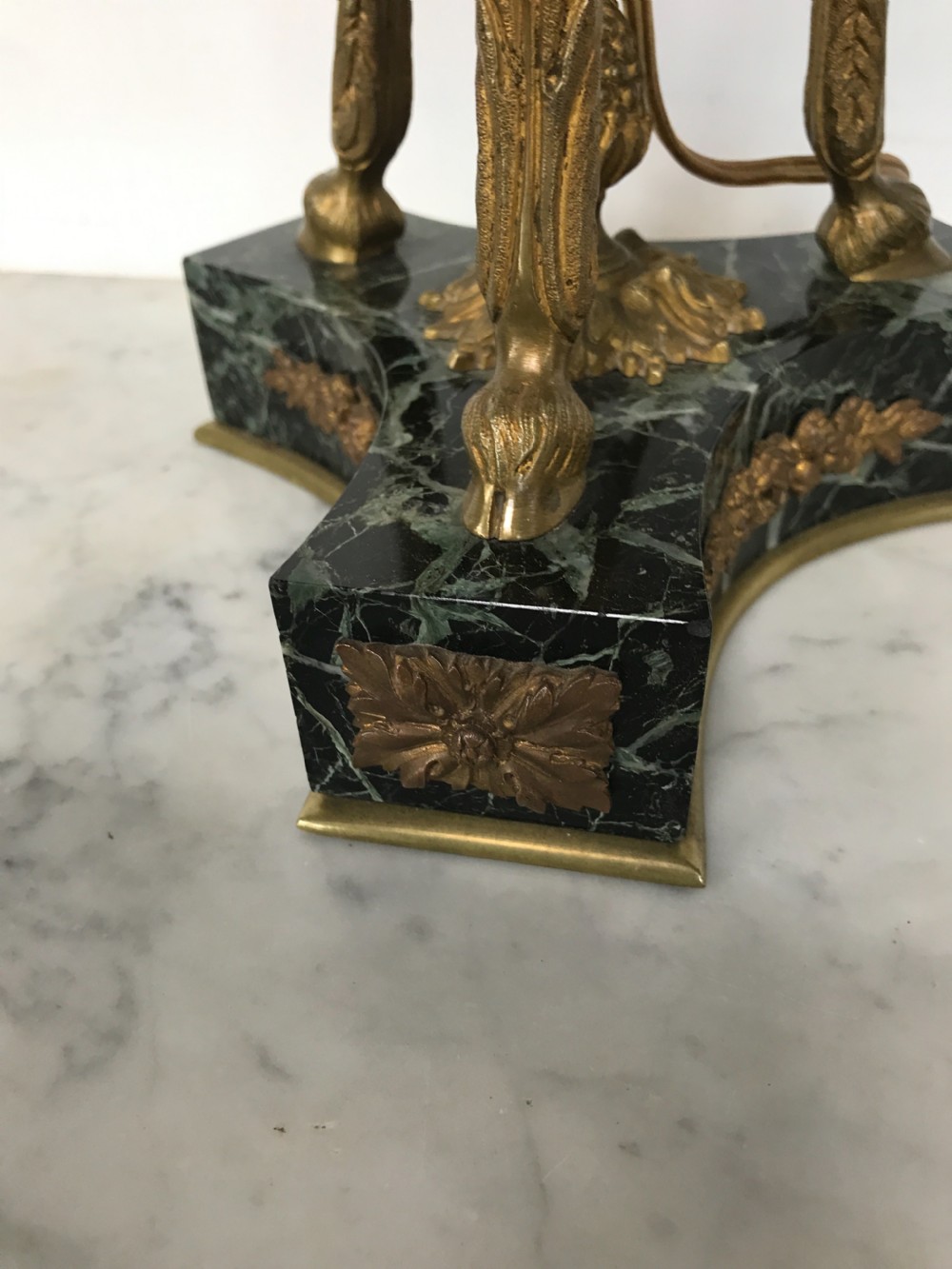 A pair of Neoclassical style table lamps fashioned as dark green marble urns supported by gilt bronze triform legs featuring rams head mounts. View IV