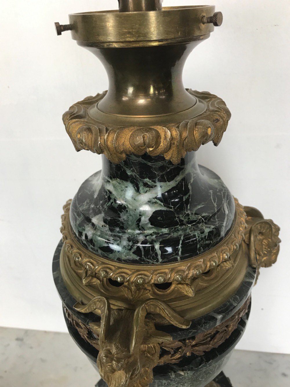 A pair of Neoclassical style table lamps fashioned as dark green marble urns supported by gilt bronze triform legs featuring rams head mounts. View VII