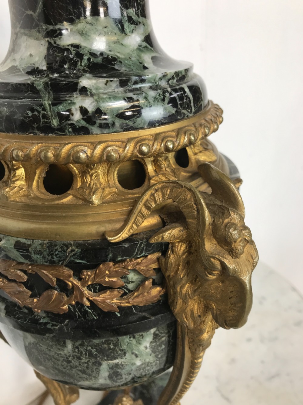 A pair of Neoclassical style table lamps fashioned as dark green marble urns supported by gilt bronze triform legs featuring rams head mounts. View VIII