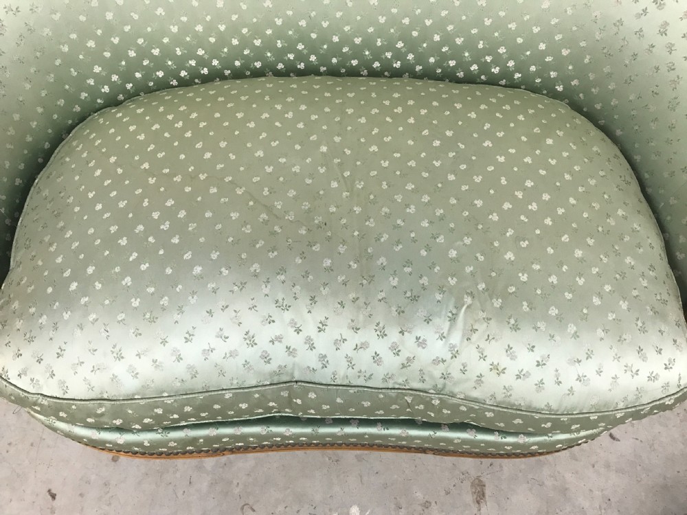 An antique French Louis XV style settee featuring a curved carved wooden frame and sage green patterned fabric upholstery with decorative studding. View IV