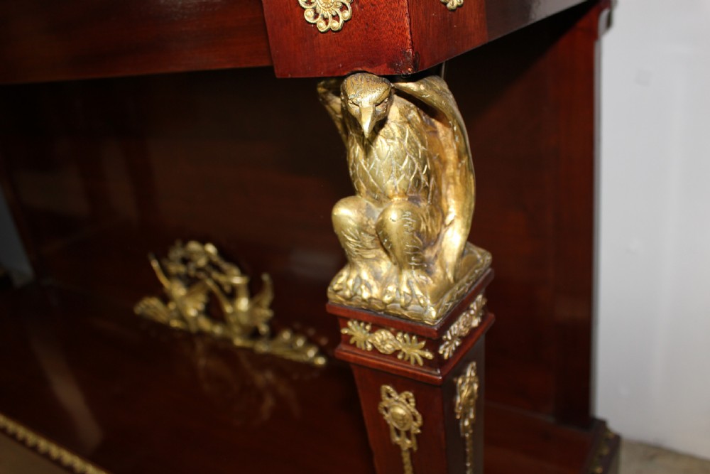 A pair of dark mahogany French Empire console tables featuring green marble tops, winged eagle supports, lower plinth shelves, and ornate gilt bronze mounts. View IV