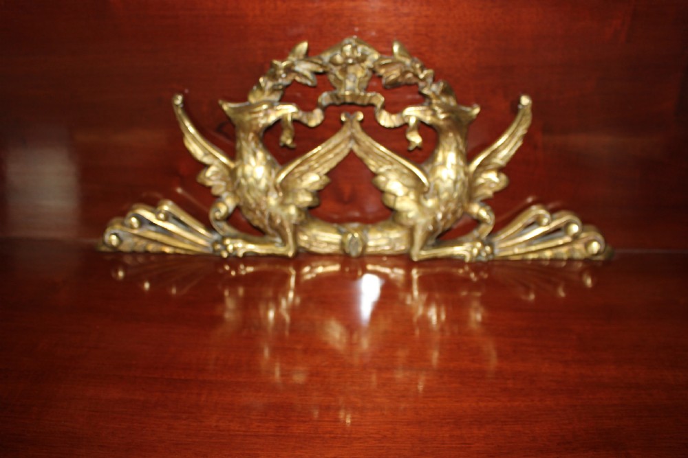A pair of dark mahogany French Empire console tables featuring green marble tops, winged eagle supports, lower plinth shelves, and ornate gilt bronze mounts. View V