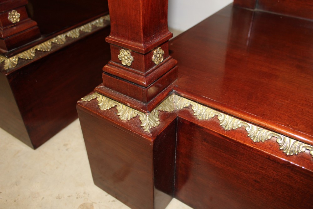A pair of dark mahogany French Empire console tables featuring green marble tops, winged eagle supports, lower plinth shelves, and ornate gilt bronze mounts. View VI