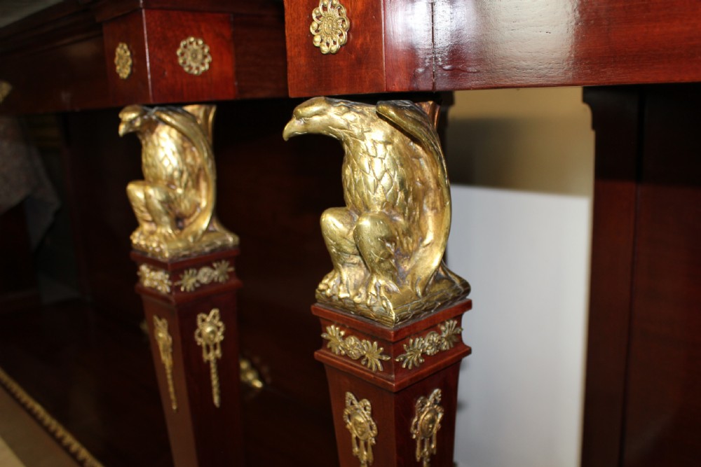 A pair of dark mahogany French Empire console tables featuring green marble tops, winged eagle supports, lower plinth shelves, and ornate gilt bronze mounts. View VII