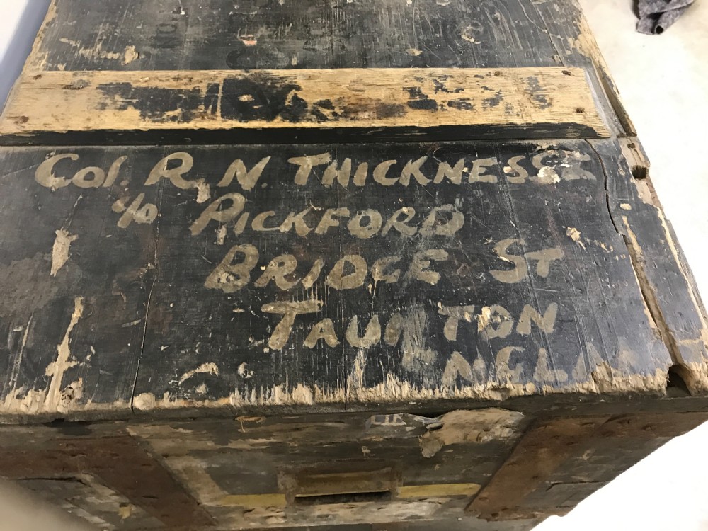 Two stacked dark painted antique wooden military trunks featuring original stencilled regimental lettering and iron brackets. View III