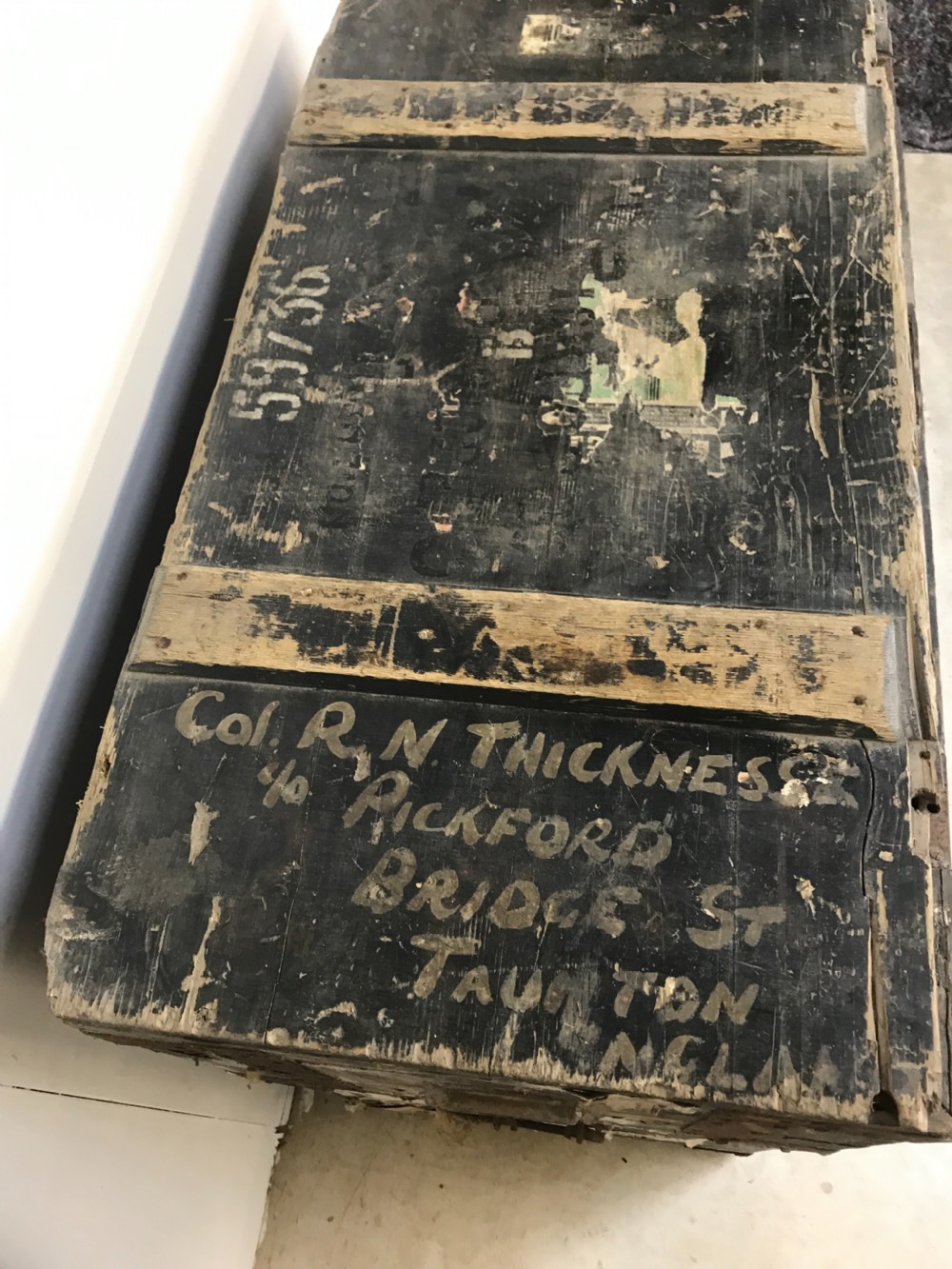 Two stacked dark painted antique wooden military trunks featuring original stencilled regimental lettering and iron brackets. View IX