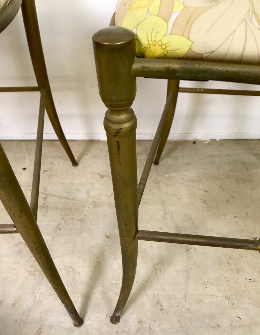 A pair of solid brass side chairs featuring ornate openwork oval backrests, slender turned legs, and yellow floral upholstered seats. View IV
