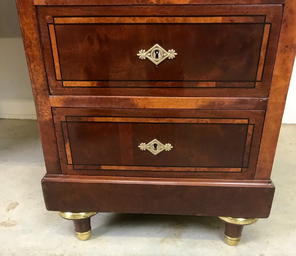 An antique mahogany pedestal desk featuring a dark leather writing top, multiple drawers with brass keyhole escutcheons, and central metal mounts. View III