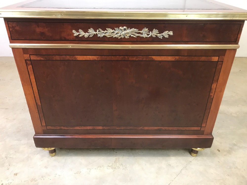 An antique mahogany pedestal desk featuring a dark leather writing top, multiple drawers with brass keyhole escutcheons, and central metal mounts. View VIII