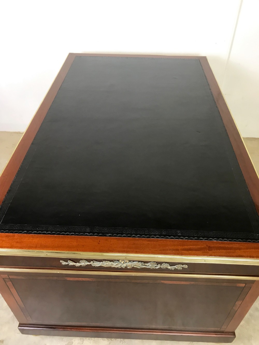 An antique mahogany pedestal desk featuring a dark leather writing top, multiple drawers with brass keyhole escutcheons, and central metal mounts. View IX