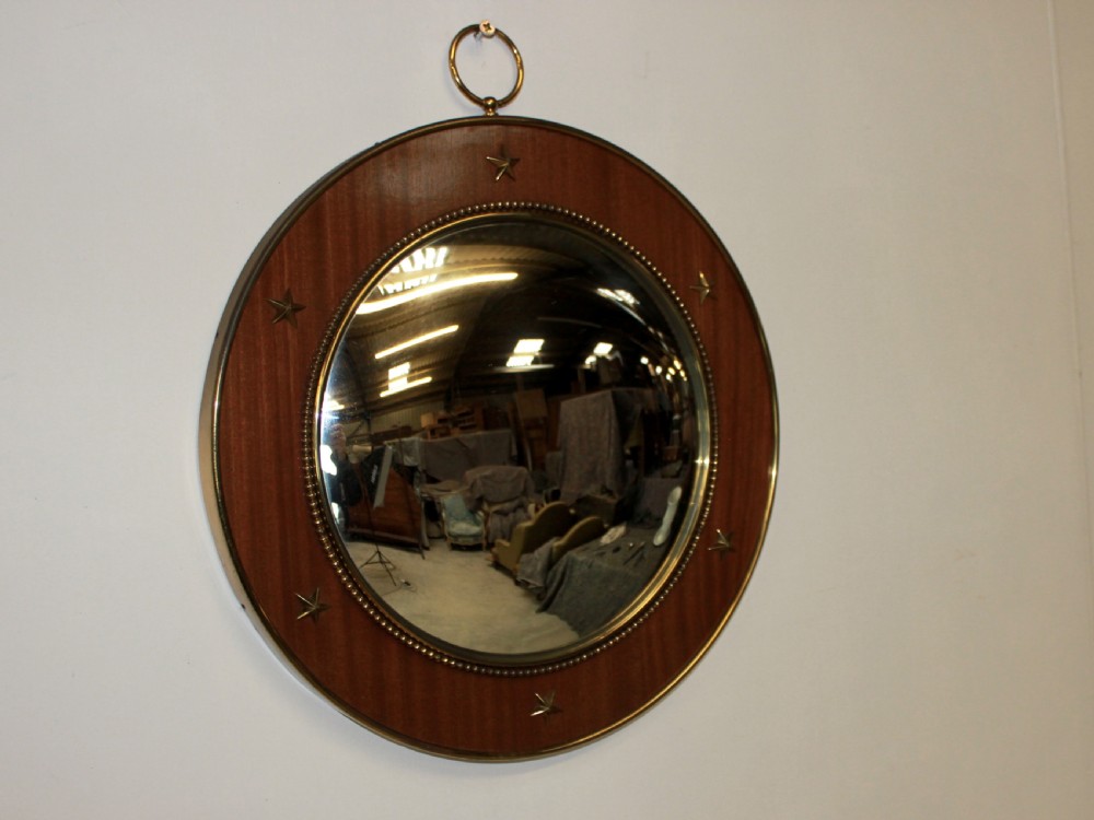 A circular mahogany convex wall mirror trimmed with brass star mounts, a beaded brass slip rim, and a top brass hanging ring.