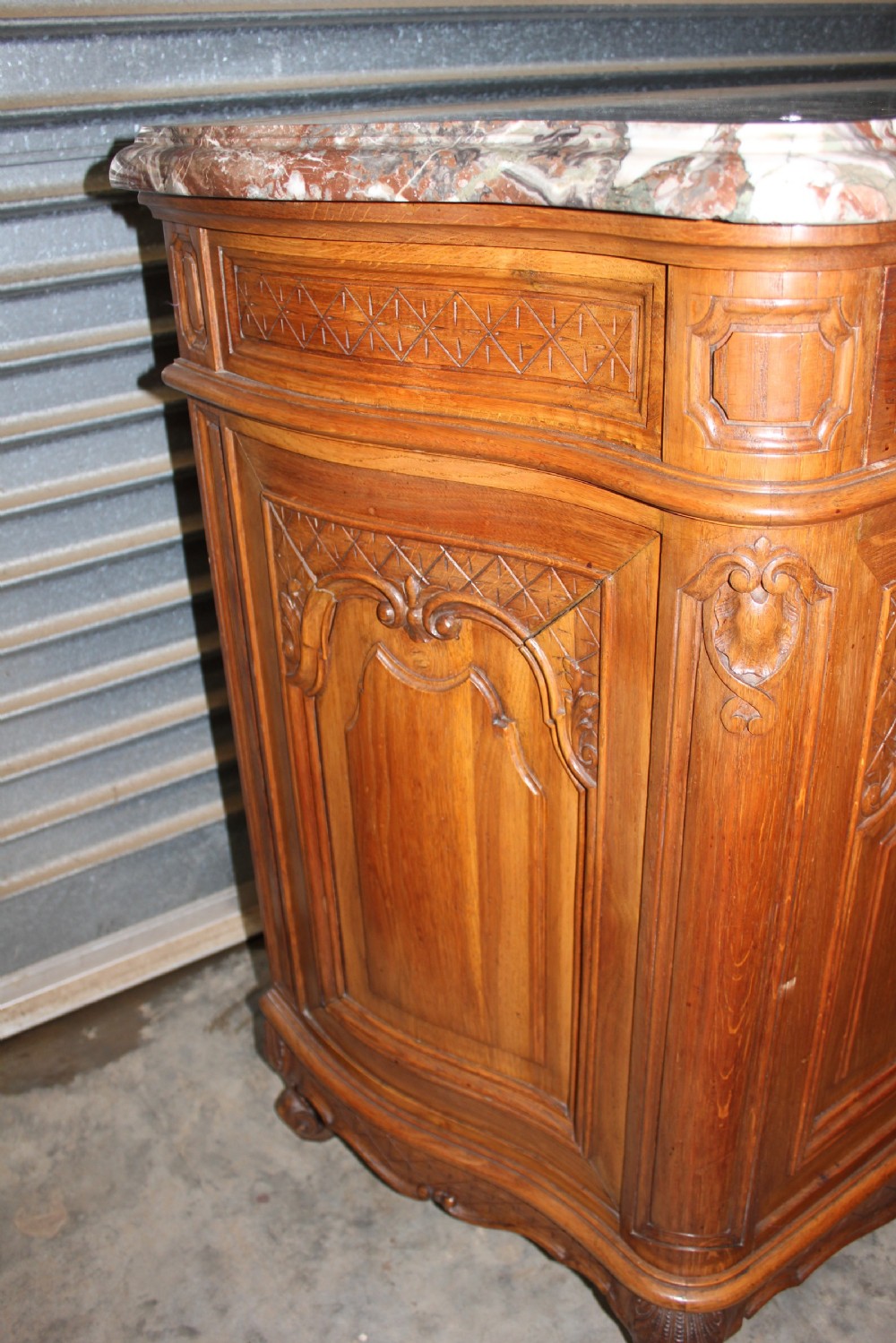 A carved French provincial oak sideboard featuring two drawers, two cabinet doors, carved geometric and floral motifs, cabriole feet, and a thick grey veined marble top. View III