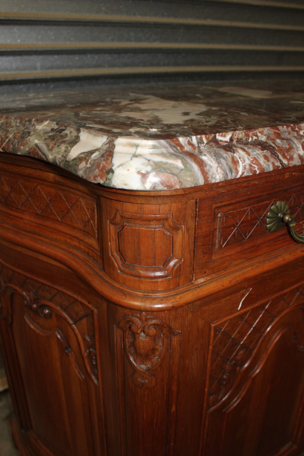A carved French provincial oak sideboard featuring two drawers, two cabinet doors, carved geometric and floral motifs, cabriole feet, and a thick grey veined marble top. View V